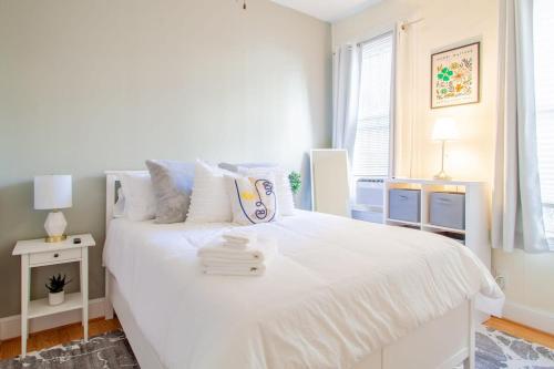 a white bedroom with a large white bed with towels on it at Classy 1-BR Flat Nestled Between Dupont & Logan in Washington, D.C.