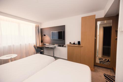a hotel room with a bed and a desk at Novotel Le Havre Centre Gare in Le Havre