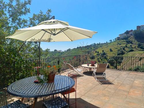 un patio con mesa y sombrilla en Beautiful House with Sea View and Nature, 30 minutes from Malaga, en Moclinejo