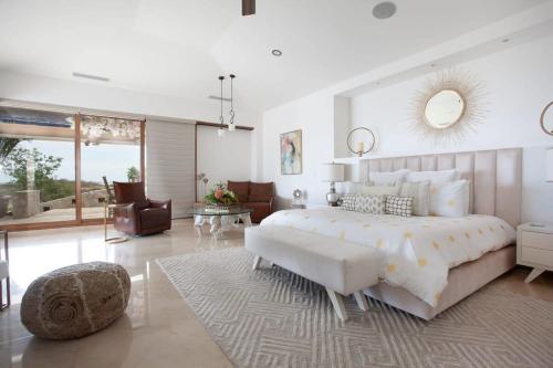 a white bedroom with a large bed and a living room at Gorgeous estate in Puerto Los Cabos golf and beach community in San José del Cabo