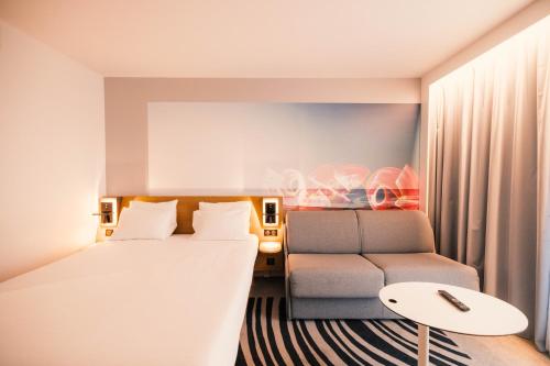 a hotel room with a bed and a couch at Novotel Le Havre Centre Gare in Le Havre