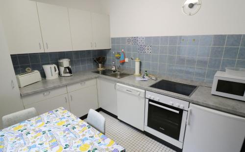 uma cozinha com armários brancos, uma mesa e um lavatório em Fewo Blumbach Nr 2, Schluchsee, Feldberg em Schluchsee