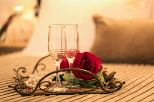 two wine glasses and a rose on a table at IRIDA COZY HOUSE στο κέντρο της πόλης in Volos