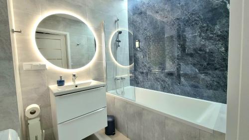 a bathroom with a tub and a sink and a mirror at NOOK NOOK Apartments Bytkowska 103 in Katowice