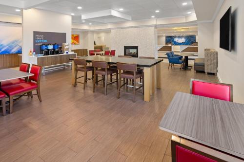 a dining room with tables and chairs in a cafeteria at Holiday Inn Express Stony Brook-Long Island by IHG in Centereach