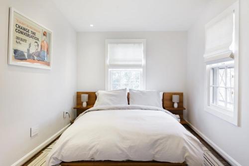 a bedroom with a bed with white sheets and two windows at Historic Charming Home in Old Town in Alexandria