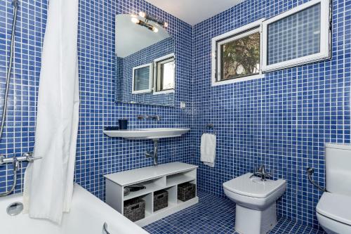 a blue tiled bathroom with a sink and a toilet at Villa Kingfisher in Cala Llonga