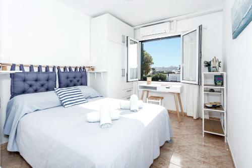 a white bedroom with a large bed and a window at Villa Kingfisher in Cala Llonga