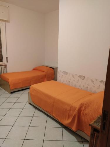 two beds with orange sheets in a room at Appartamento Cesena, 2 camere 4 posti letto in Imola