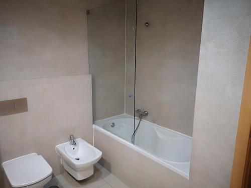 a bathroom with a toilet and a tub and a sink at Rocha T Apartments in Portimão