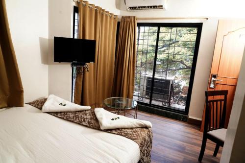 a hotel room with a bed and a large window at Hotel Padma Krishna in Pune
