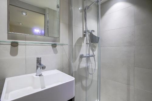 une salle de bain avec un lavabo et une douche avec un miroir dans l'établissement Maison Bianchi - Jean Médecin, à Nice
