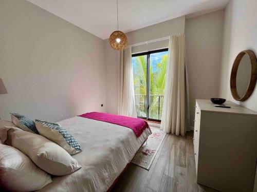 a bedroom with a bed with a window and a mirror at Summer beachfront apartment in Belle Mare