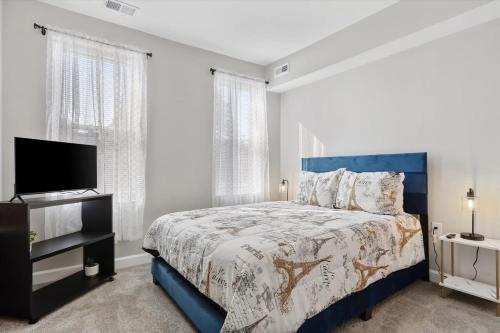 a bedroom with a blue bed and a flat screen tv at Charm City Homestay in Washington Village in Baltimore