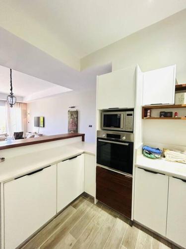 a kitchen with white cabinets and a black oven at Summer beachfront apartment in Belle Mare