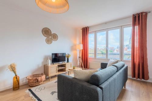 a living room with a blue couch and a large window at One bedroom apartment with balcony, city center in Tourcoing