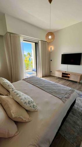 a bedroom with a large bed with a large window at Summer beachfront apartment in Belle Mare