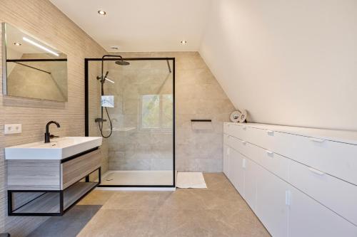 ein Bad mit einer Dusche und einem Waschbecken in der Unterkunft Maison Malo in De Haan