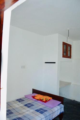 a small bed in a room with a white wall at Ithin Kithul Villa in Beragala