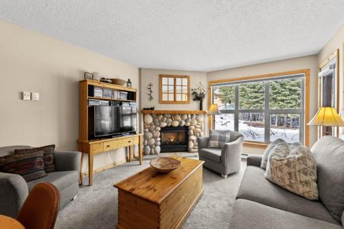 a living room with a fireplace and a tv at Crystal Forest #51 condo in Sun Peaks
