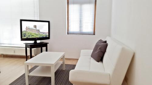 ein weißes Wohnzimmer mit einem weißen Sofa und einem TV in der Unterkunft Alte Uhrmacherei Eisenach in Eisenach