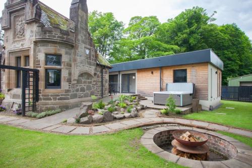 a stone house with a fire pit in the yard at Stylish Loch Lomond lodge in stunning surroundings in Balloch