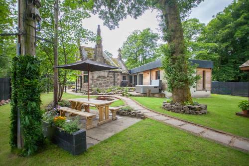 a backyard with a picnic table and an umbrella at Stylish Loch Lomond lodge in stunning surroundings in Balloch