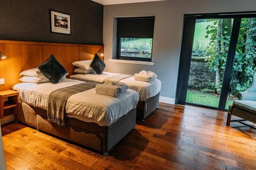 a bedroom with two beds and a large window at Stylish Loch Lomond lodge in stunning surroundings in Balloch