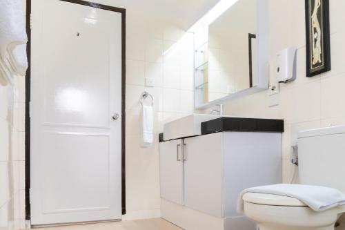 a white bathroom with a toilet and a sink at LA CASA BORNEO in Bentakan Kecil