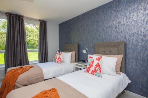 Duas camas num quarto com papel de parede azul em Beautiful West End Flat with Private Parking em Glasgow