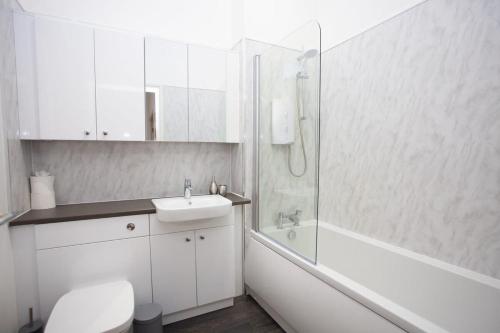 La salle de bains blanche est pourvue d'un lavabo et d'une douche. dans l'établissement Glasgow Green Getaway with Free Parking, à Glasgow