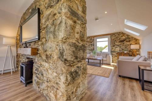 - un grand mur en pierre dans le salon doté d'une cheminée dans l'établissement Blar Cottage (Private Sauna + Fast Starlink Wifi), à Hayfield