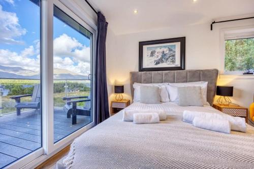 a bedroom with a large bed and a balcony at New Build Lodge With Stunning Views of Loch Awe in Hayfield
