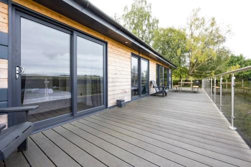 a large deck with glass doors andwindows on a house at New Build Lodge With Stunning Views of Loch Awe in Hayfield