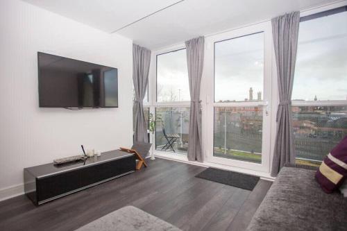 a living room with a flat screen tv and large windows at Beautiful Flat with Panoramic Views over the City in Glasgow