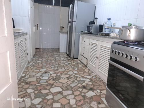 uma cozinha com um frigorífico e piso em azulejo em Yulendo em Beira
