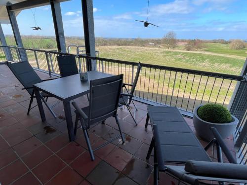a table and chairs on a balcony with a view of a field at Ostseetraum - Lütt Heimaad Whg 32 - Hohen Wieschendorf in Hohen Wieschendorf