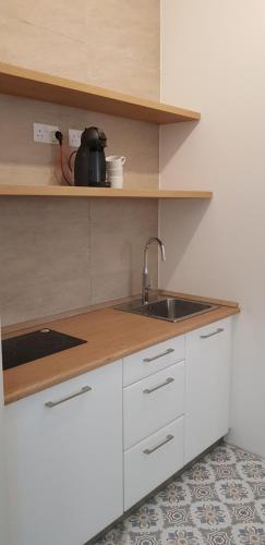 a kitchen with white cabinets and a sink at Bright & modern studio,Sliema in Sliema