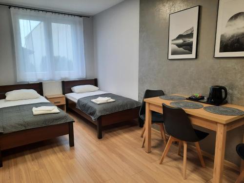 um quarto com duas camas e uma mesa e cadeiras em Hotelik Corner em Ketrzyn