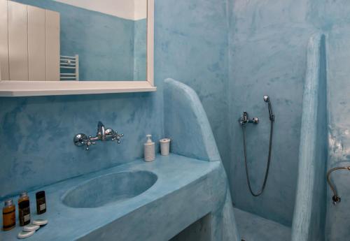 a blue bathroom with a sink and a shower at Artemis Apartments in Tinos Town