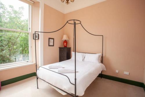 Schlafzimmer mit Himmelbett und Fenster in der Unterkunft Bright Spacious 3 Bed Flat in Glasgow