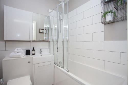 a white bathroom with a shower and a toilet at Bright Spacious 3 Bed Flat in Glasgow