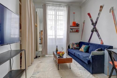 a living room with a blue couch and skis on the wall at 372 Suite Saulnier 2 - Superbe Appartement à Paris in Paris