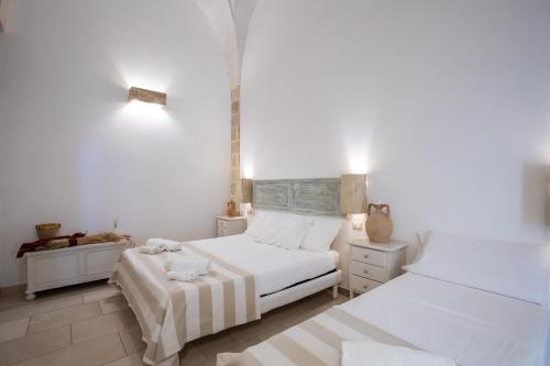 1 dormitorio blanco con 2 camas y mesa en Casale Donna Rosa, en Sannicola