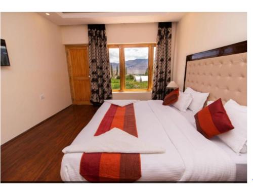 1 dormitorio con 1 cama grande y ventana grande en Kartok resort, Leh, en She