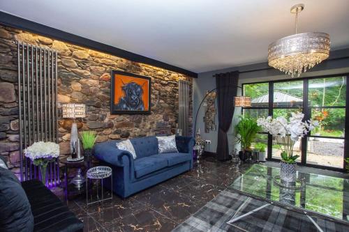 a living room with a blue couch and a stone wall at The Ultimate Luss Retreat in Luss