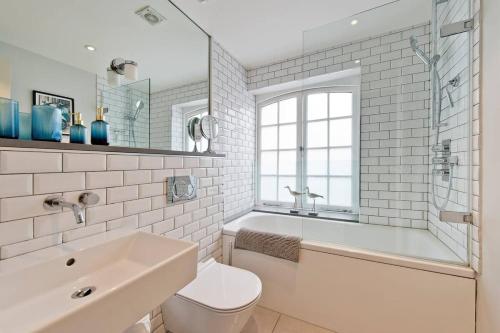 y baño con bañera, aseo y lavamanos. en *Newly Renovated 2-Bed in Heart of Notting Hill*, en Londres