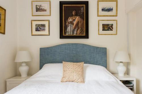 1 dormitorio con 1 cama con cabecero azul y cuadros en la pared en Artistic 1bed flat with patio in South Kensington, en Londres