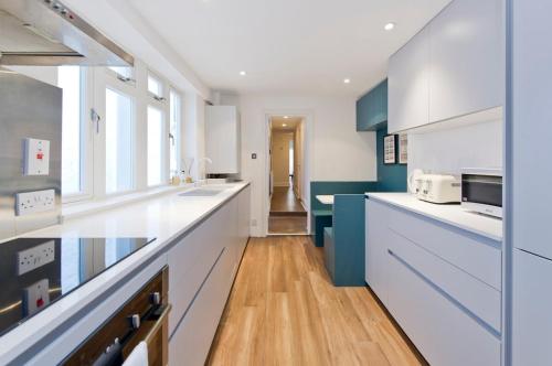 a kitchen with white counters and blue cabinets at Charming 2-Bed Apt, Pimlico in London
