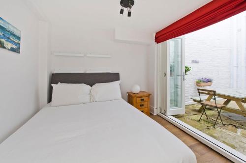 a bedroom with a large white bed and a window at Charming 2-Bed Apt, Pimlico in London